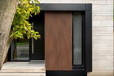 a black and brown door on the side of a building next to a tree in front of it