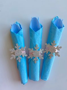 three blue napkins with silver snowflakes on them are sitting next to each other