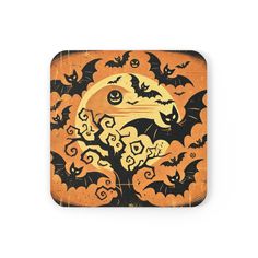 an orange and black square coaster with bats flying over the moon in front of it