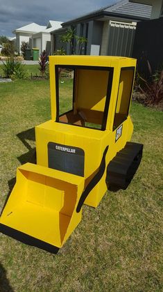 a construction vehicle made out of cardboard sitting in the grass