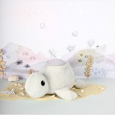 a white stuffed animal laying on top of a sandy beach next to a wall mural