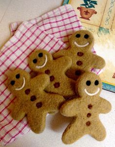 several ginger cookies with faces and eyes are on a towel next to an open book