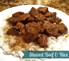 a white plate topped with rice and meat covered in gravy on top of a counter