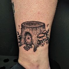 a person with a tattoo on their leg that has a tree stump and mushrooms in it