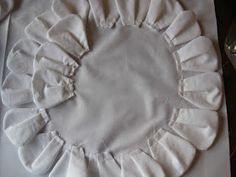 a white cloth with ruffles on it sitting on top of a cutting board