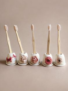 five toothbrushes lined up in the shape of flower heads, all with wooden handles