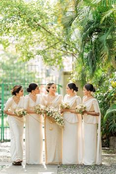 a group of women standing next to each other in front of trees and greenery