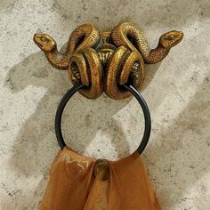 a gold snake head hanging on the wall with a black ring around it's neck