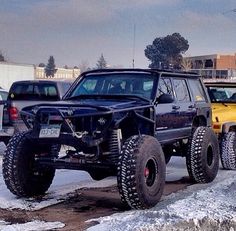 the jeep is parked on the side of the road in front of other cars and trucks