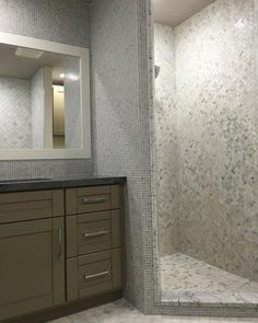 a bathroom with a walk in shower next to a sink and mirror on the wall