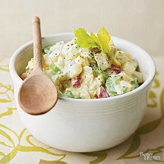 a white bowl filled with pasta salad and a wooden spoon on top of a table