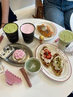 a white table topped with plates and cups filled with desserts next to each other