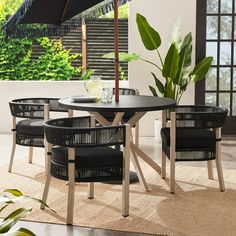 an outdoor table and chairs with an umbrella in the middle of it on a rug