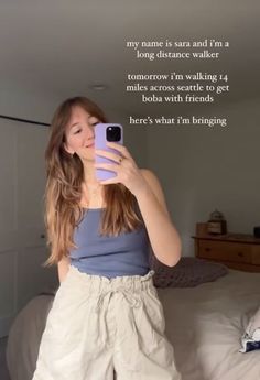 a woman taking a selfie with her cell phone while standing in front of a bed