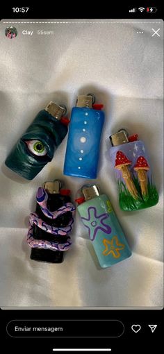 several lighters with designs on them sitting on a white sheet in front of a cell phone