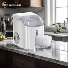 a white ice maker sitting on top of a kitchen counter next to a bowl of fruit