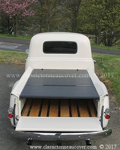 the back end of an old pickup truck with its flatbed open and wood flooring