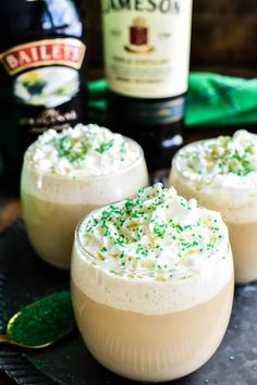 three glasses filled with whipped cream and sprinkles next to a bottle of jameson