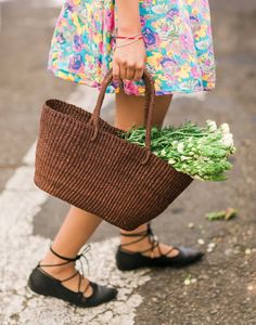 a woman is carrying a basket full of flowers