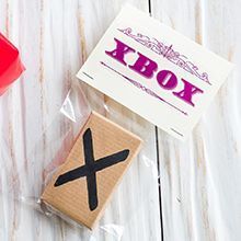 a rubber stamp with the word x on it next to a red cup and box