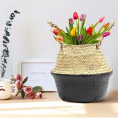 a basket with flowers in it sitting on a table next to a cup and vase