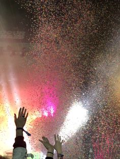 two people are reaching up to catch confetti in the air with their hands