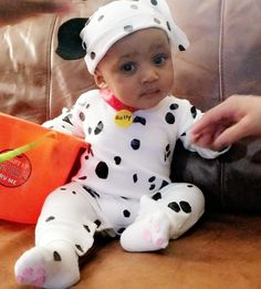 a baby wearing a dalmatian costume sitting on a couch