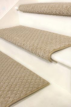 a carpeted stair tread on the side of a white staircase with beige rugs