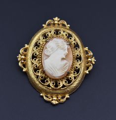 Elevate your style with our hand-carved shell lady cameo pin, a true vintage masterpiece signed by Florenza. This large oval brooch exudes elegance and uniqueness, making it the perfect quirky jewelry gift for women who appreciate timeless beauty. Shop now for this exquisite accent piece and add a touch of vintage charm to your collection. Vintage  from before 1960s Length: 2.2 Inches;  Width: 1.8 Inches  Materials: gold tone metal  Style: Victorian 13BJ 🎁 And if you happen to be a gentleman shopping for a gift for your lady, here's a couple of tips: 1) There's no such thing as "too much jewelry". 2) Any woman would love jewelry as a gift regardless of her age - and yes, that includes your grandma. 3) Designer jewelry is always a safe choice - you don't have to worry that she might have a Luxury Cameo Brooches As Gifts, Luxury Classic Cameo Brooch, Luxury Cameo Brooch As Gift, Luxury Cameo Brooches For Gift, Luxury Vintage Oval Brooch, Luxury Oval Filigree Brooches, Luxury Elegant Cameo Jewelry, Luxury Cameo Brooch, Real Pearl Jewellery