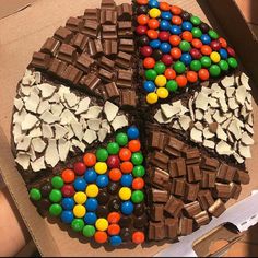 a chocolate cake decorated with m & m candies and other toppings in a box