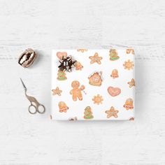 a wrapping paper with ginger cookies on it next to some scissors and other things that are laying around