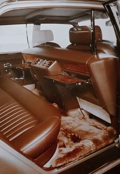 the interior of an old car with brown leather seats and fur rugs on the floor