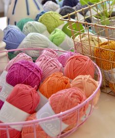 several balls of yarn are in a basket on the table next to each other,