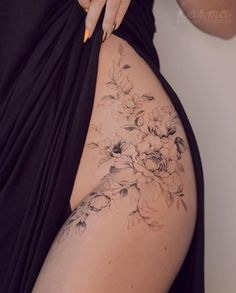 a woman's thigh with flowers on it and her hand holding the side of her body