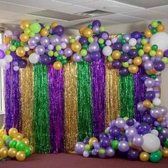 an arrangement of balloons and streamers in purple, green, gold and white colors