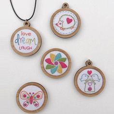 four embroidered ornaments are hanging on a white wall and one has the words love, dream, laugh