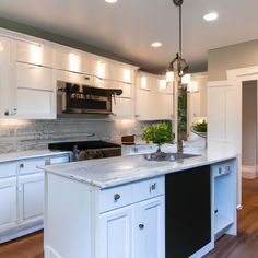 a large kitchen with white cabinets and an island in the center is lit by recessed lights