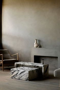 a living room with two chairs and a table in front of a fire place next to a fireplace