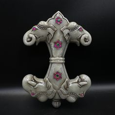 an ornate metal object with pink and white flowers on it's sides, against a black background