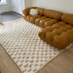 a large brown couch sitting on top of a wooden floor next to a white rug