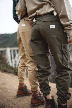 two people standing next to each other on a dirt road