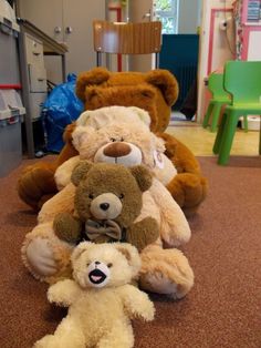 four teddy bears sitting in a row on the floor