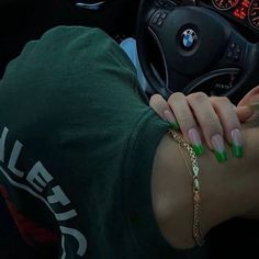 a woman with green nail polish on her nails is sitting in the drivers seat of a car