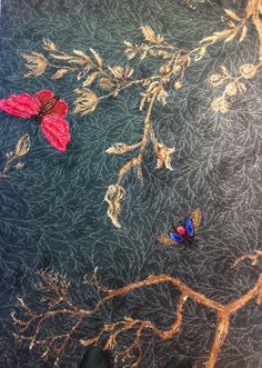 two butterflies sitting on top of a piece of cloth with gold and red leaves in the background