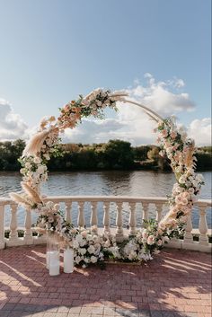 a wedding arch decorated with white flowers and pamolite on the side of a river