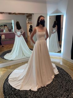 a woman is standing in front of a mirror wearing a wedding dress