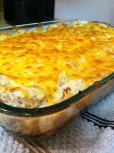 a casserole dish with cheese and meat in it sitting on a towel next to a glass bowl