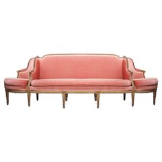 an old fashioned pink couch with wooden legs