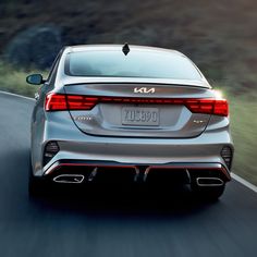 the rear end of a silver car driving down a road