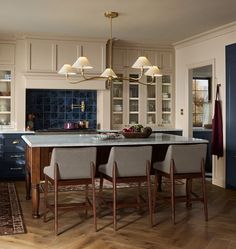 a large kitchen with an island in the middle and chairs at the end, along with blue cabinets